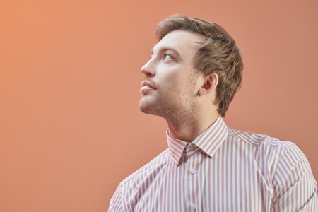 Business style. Portrait of a middle-aged business man in a classic striped shirt, looking aside with a slight smile. Successful people. Studio portrait on an orange background with copy space.の写真素材