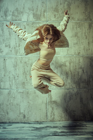 Modern style dancer girl jumping against a grunge studio background. Contemporary dances.の写真素材