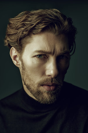 Art portrait in a dark key of a handsome forty-year-old man with curly hair, dressed in a black...
