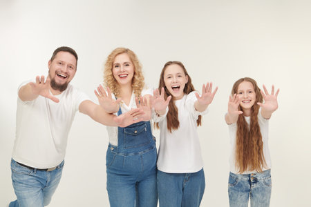 Portrait of a happy and friendly family. Beautiful happy mother and father with their beloved daughters posing together in white t-shirts on a white studio background.の写真素材