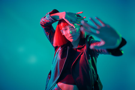 Sci-fi cyborg girl. An attractive cyberpunk girl poses against a blue background in mixed light....