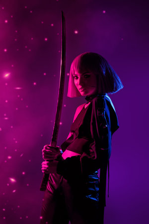 Portrait of a militant cybergirl standing on alert with a sword. Neon crimson purple lighting. Space...