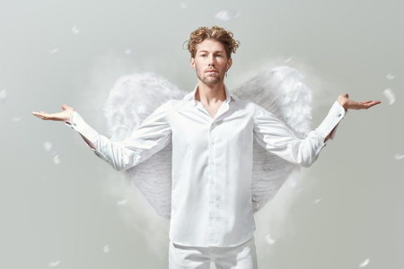 God of love Cupid. Courageous handsome male Cupid angel in white clothes and with white wings. White background. Valentine's Day.の写真素材