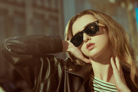 Attractive young woman. Modern young woman posing on a city street in black leather jacket and...