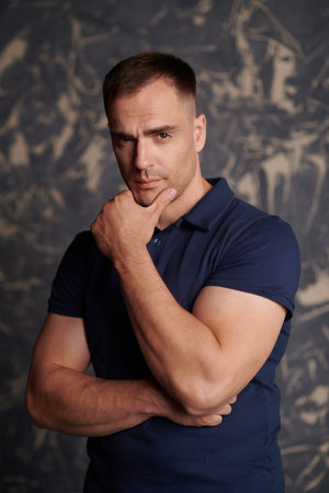 Portrait of handsome masculine man with athletic build posing in studio. Male beauty and health....