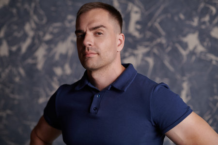Handsome muscular man looks at the camera confidently and with a smile. Studio portrait. Active...
