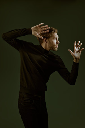 Art portrait in a dark key of a handsome forty-year-old man with curly hair, dressed in a black...