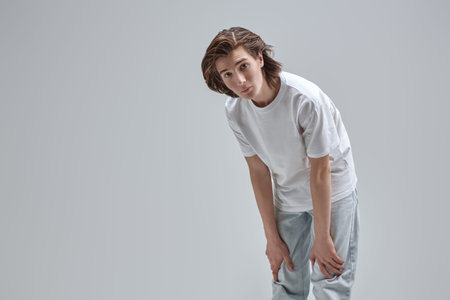 Modern lifestyle. People and emotions. Portrait of handsome teen boy in white t-shirt looking at...