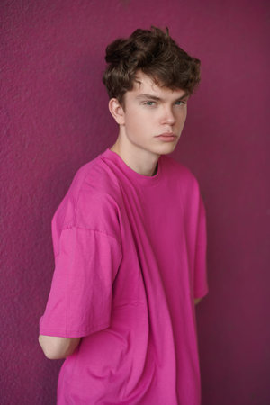 Youth Fashion. Portrait of a modern young male fashion model in a crimson t-shirt on a purple background. Men's hairstyles.の写真素材