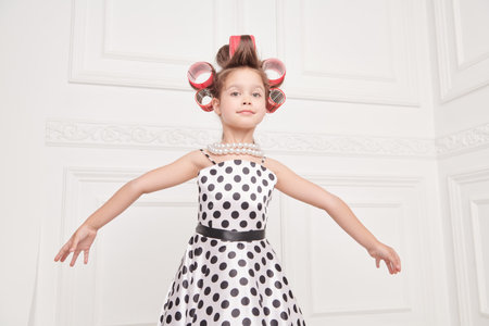 Little ballerina. A little pretty girl in an elegant polka-dot dress and curlers on her head is going to a party. Pin-up style. Kid's Fashion - clothes and accessories.の写真素材