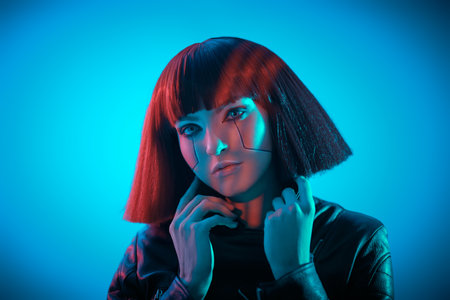 Cyberpunk concept. Portrait of a beautiful cyberpunk girl with bright red makeup and red hair posing in dark light. Virtual games. Makeup and hairstyle.の写真素材