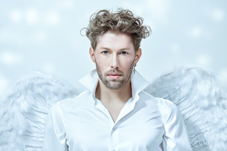 Courageous handsome male Cupid angel in white clothes and with white wings. White background. Valentine's Day. God of love Cupid.の写真素材