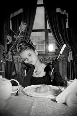 A pretty little girl is in an expensive restaurant. Black and white retro portrait. Elegant evening...