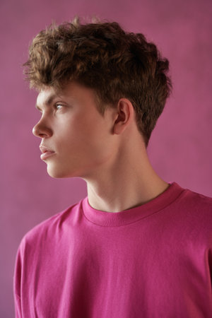 Male beauty. Youth Fashion. Sideview portrait of a modern young male fashion model in a crimson sweatshirt on a purple background. Men's hairstyles.の写真素材