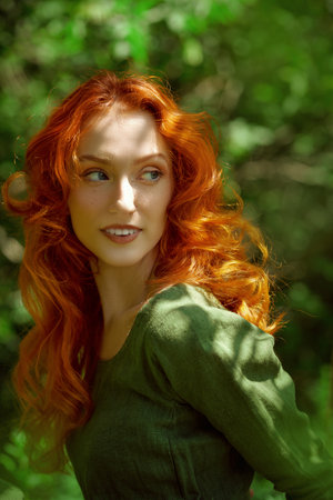 Portrait of a beautiful red-haired girl of the Middle Ages walking in the dense forest. Celtic culture. Fantasy world.の写真素材