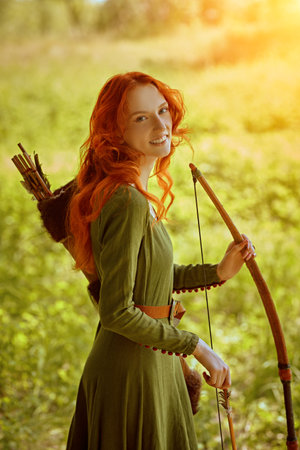 Fantasy heroine. Beautiful and brave young woman archer with magnificent long red hair in a...