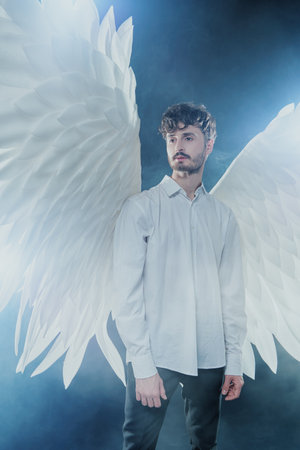 The male guardian angel looks aside with calm and hope in his eyes. Heavenly light surrounds him.の写真素材