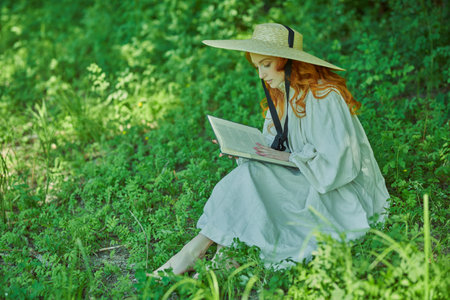 A beautiful romantic girl with charming wavy red hair, dressed in a long white shirt and a...