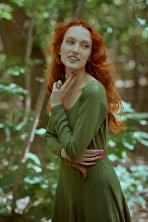 Celtic culture. Fantasy world. Portrait of a beautiful red-haired girl of the Middle Ages walking in the dense forest.の写真素材
