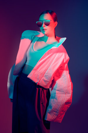 Fashion and haute couture style. Beautiful fashion model girl posing in stylish clothes with wide oversized shapes. Studio shot against a dark background in mixed color light. Bright colors.の写真素材