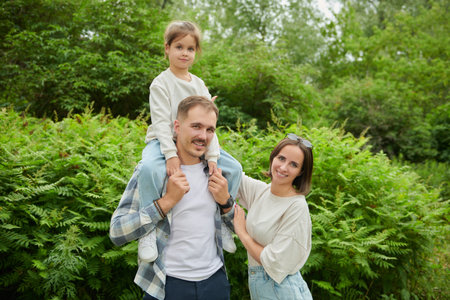 A cheerful friendly family of parents and daughter relax in the summer park. Summer time and...