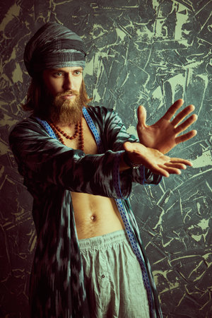 A man with the appearance of a hippie rastaman is doing some shaman ritual. Grunge background.の写真素材