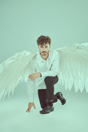 The male guardian angel looks with calm and hope in his eyes. Full-length studio portrait with white background.の写真素材