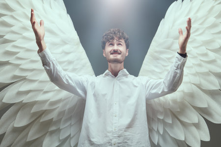 The male angel stretches out his hands to the heavens with a look of happiness on his face. Heavenly light illuminates him from above.の写真素材