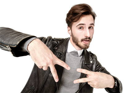 Men's fashion style. Portrait of handsome confident man in black leather jacket posing in motion at studio. White background. People, emotions.の写真素材