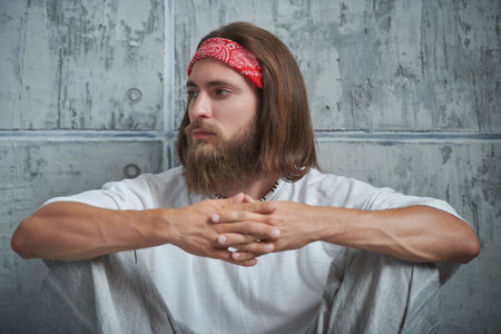 Rastaman hippie guy sits relaxed near a grey wall.の写真素材