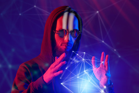 Lifestyle. A shot of a brutal shaven-headed bearded man with a lip piercing and wearing black sunglasses and black hoodie. Studio shot against a dark purple background in mixed red and blue light.の写真素材