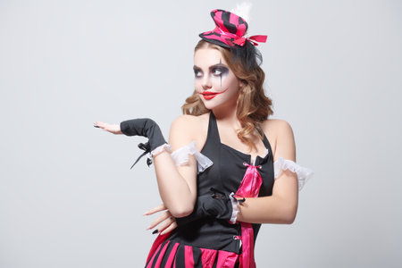 Character for Halloween. Portrait of a beautiful and scary young clowness against a white background. Makeup and hairstyle. Beauty and Horror. Space for text.の写真素材