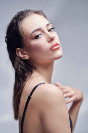 Beauty of women. Portrait of an attractive brunette girl with elegant makeup posing on a light grey background. Cosmetics, skincare.の写真素材