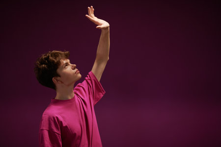 Men's hairstyles. Profile portrait of a modern young man fashion model in a crimson sweatshirt on a purple background with copy-space. Youth Fashion. Emotions.の写真素材