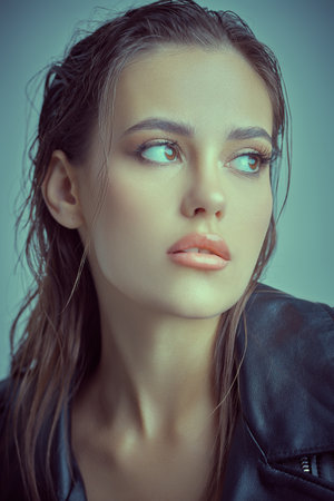 Portrait of a sexy brunette girl in black leather jacket on a light blue studio background. Women's Fashion. Cosmetics and makeup.の写真素材