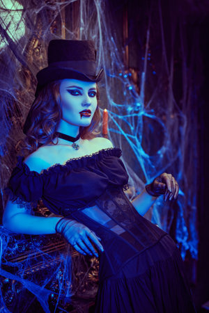 A beautiful sexy vampire lady in a 19th century style dress and hat stands in an abandoned castle...
