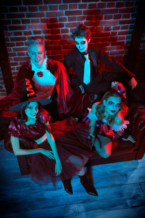 Portrait of teenage friends in carnival costumes having fun celebrating Halloween. Skeleton, witch, clown and vampire. Merry Halloween party.の写真素材
