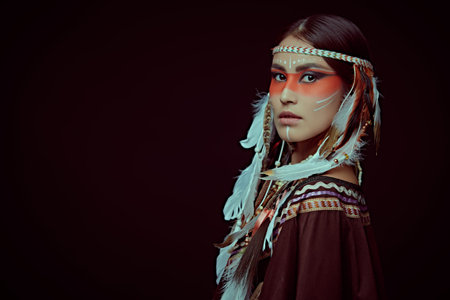 Portrait of a beautiful American Indian girl in traditional dress and jewelry on a black background....