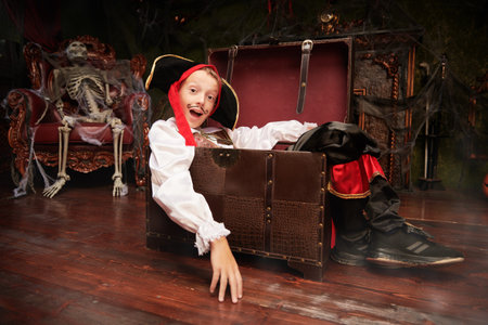 Halloween story. Cheerful child boy in a costume of a pirate is in an old castle with cobwebs at Halloween.の写真素材
