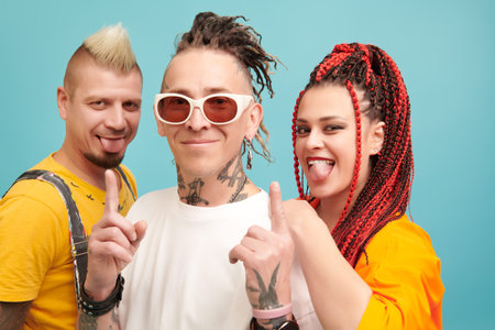 Vibrant lifestyle. Three cool emotional young people with freaky hairstyles and dressed in bright...