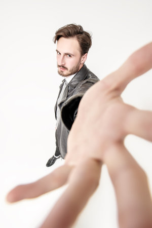 Fashion for men. Full length portrait of handsome confident man in black trousers and black leather jacket posing in motion at studio. White background.の写真素材