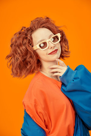 Bright colors. Portrait of a beautiful confident girl with foxy curly hair smiling in bright blue...