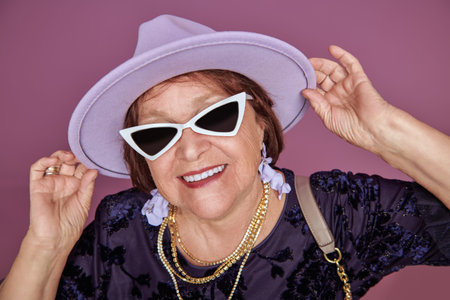 Happy elderly woman dressed in fashionable clothes and accessories smiles at the camera. Retirement...