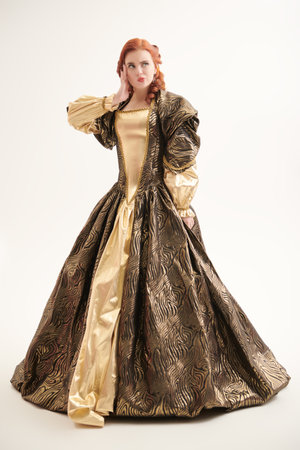 Full-length portrait of a cool beautiful red-haired princess in a puffy brown and gold dress on a...