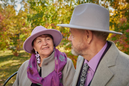 Happy retirement age. A beautiful and happy elderly couple is walking and chatting in an autumn park.の写真素材