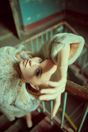 A chic, elegant lady in an expensive mink coat stands on the stairs of an old house. Expensive lifestyle and glamour. Fashion shot.の写真素材