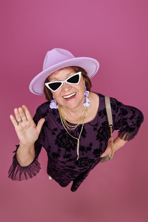 Portrait of a positive fashionable older woman on a purple studio background. Fashion and style for...