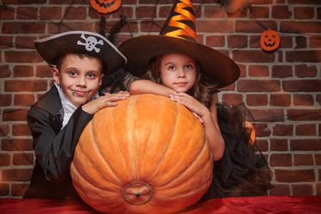 Two kids in carnival costumes get scared and happy at a Halloween party. Halloween celebration.の写真素材