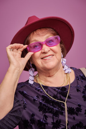 Portrait of a beautiful emotional elderly woman wearing fashionable clothes and accessories on a...
