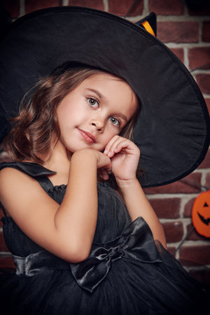 Halloween holiday. Portrait of a little cute girl in a witch costume ready for the Halloween celebration.の写真素材